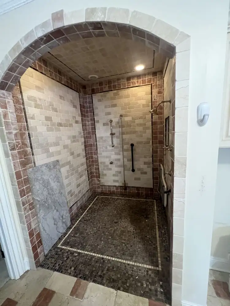 Arched walk-in shower with dated tumbled stone tile before remodel, Avon Lake, Ohio