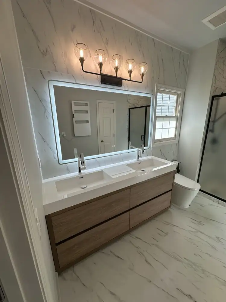 Wood double vanity with lighted mirror, globe light fixture and marble-look wall tile, Ohio