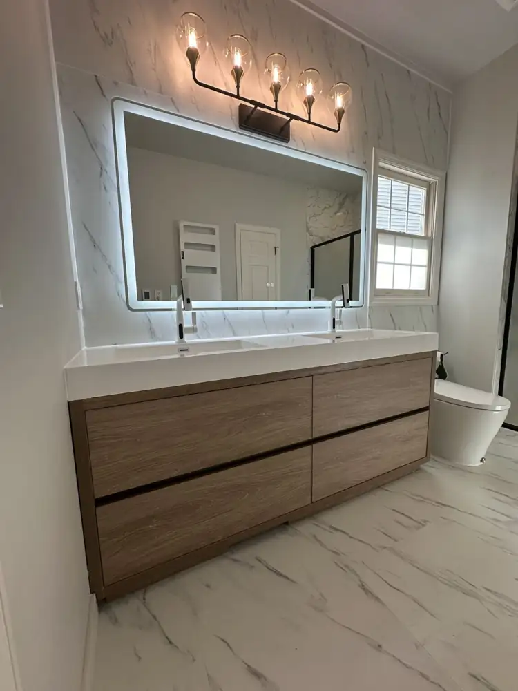 Another view: Bathroom with marble-look porcelain floor and feature wall, wood double vanity, lighted mirror and black-framed shower, Aurora, Ohio