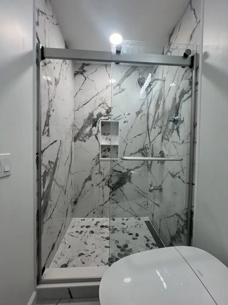 Walk-in shower with large-format marble-look porcelain, hex mosaic floor, niche, linear drain and sliding glass door, Ohio
