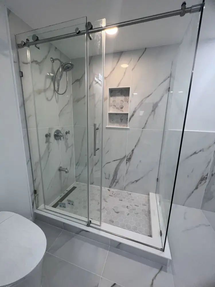 Glass sliding-door shower with marble-look porcelain walls, hex mosaic floor and niche, Beachwood, Ohio