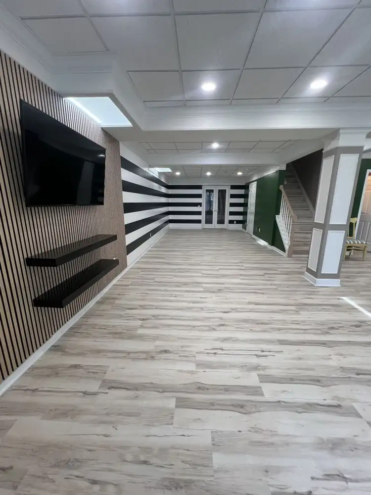 Remodeled basement with slat wall, bold black-and-white striped walls, green accent wall and light plank flooring, Bedford, Ohio