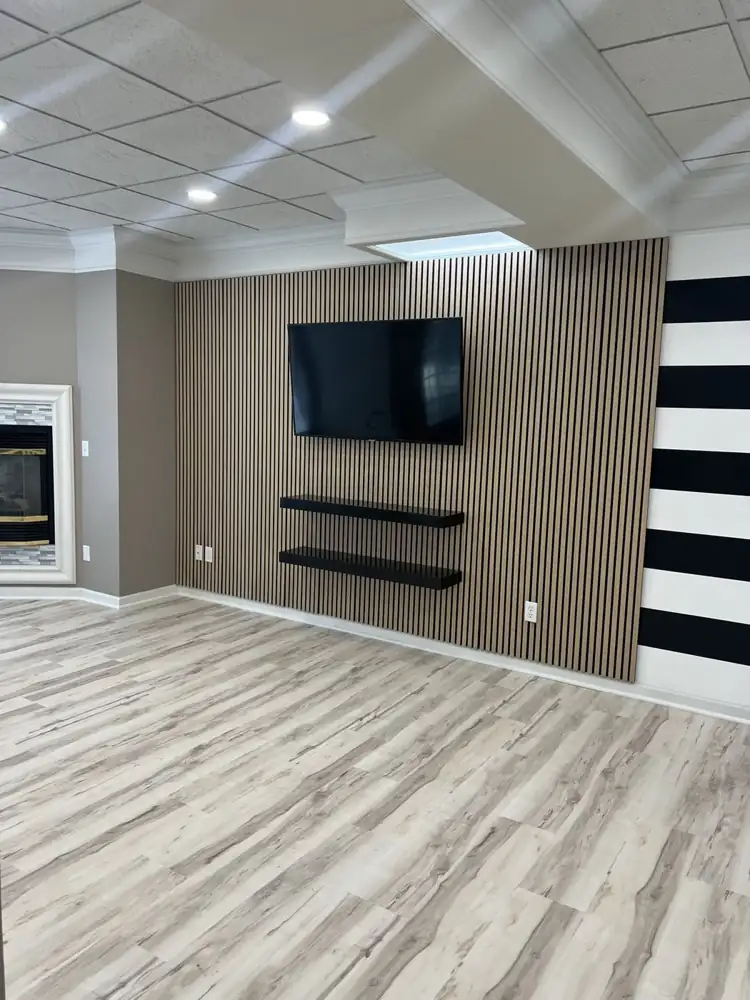 Basement accent wall with wood slat panels, mounted TV, floating shelves and plank flooring, Bedford, Ohio