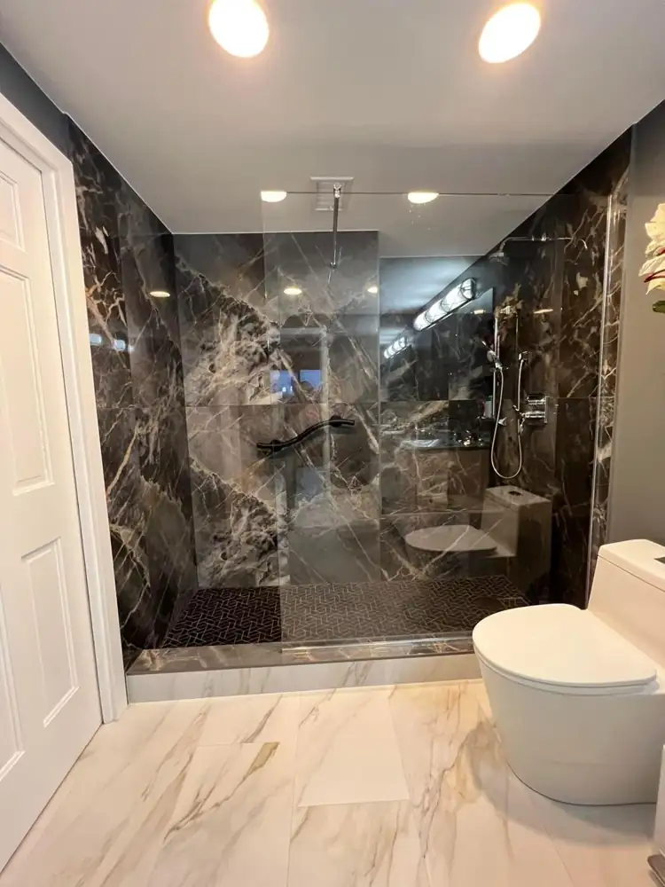 Another view: Walk-in shower with dark marble-look porcelain, glass panel and grab bar, gold-veined floor tile, Bratenahl, Ohio
