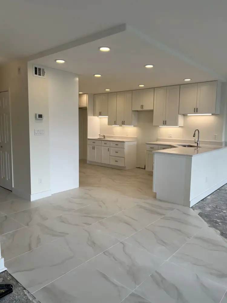 New white shaker kitchen with quartz counters, under-cabinet lighting, recessed lights and large-format marble-look tile, Bratenahl, Ohio