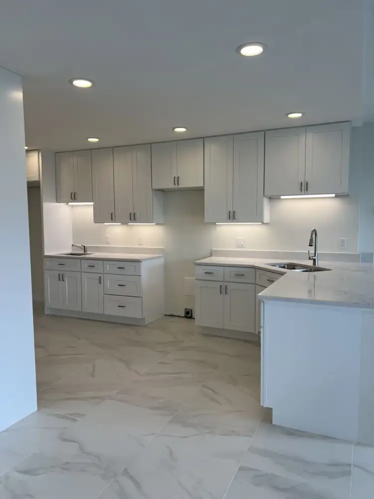 Another view: New white shaker kitchen with quartz counters, under-cabinet lighting, recessed lights and large-format marble-look tile, Bratenahl, Ohio