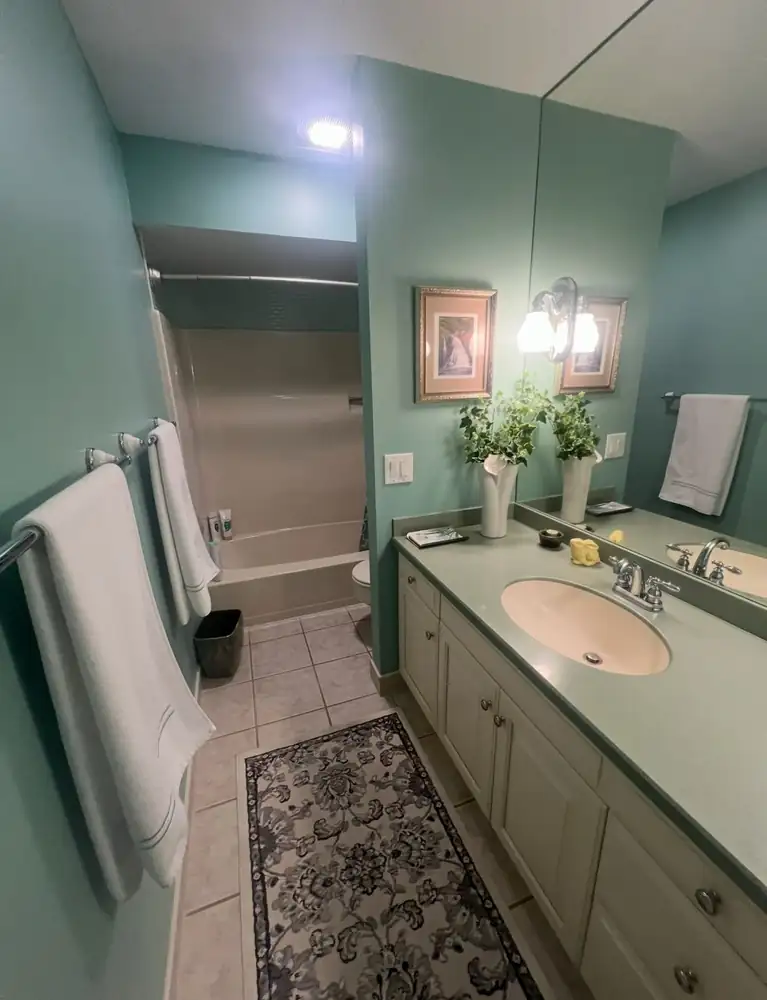 Dated teal bathroom with fiberglass tub and green laminate vanity before remodel, Brecksville, Ohio