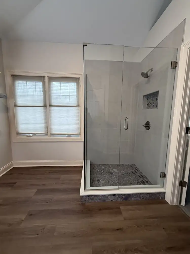 Frameless glass walk-in shower with terrazzo-look floor and niche, linear drain and quartz curb, Ohio