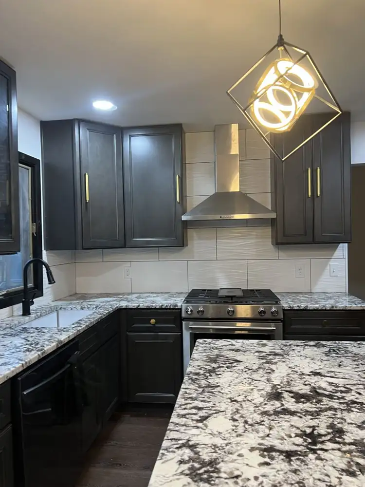 Another view: New kitchen with dark cabinets, brass pulls, granite counters, large island and luxury vinyl plank floor, Beachwood, Ohio