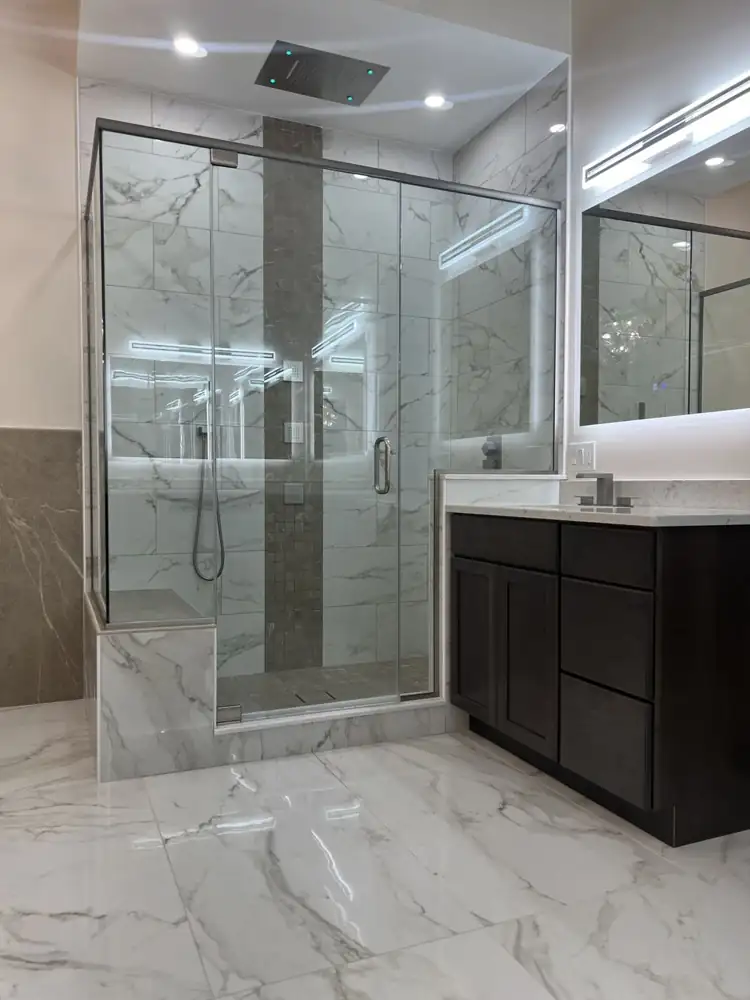 Another view: Primary bathroom with freestanding tub, glass chandelier, frameless glass shower with ceiling rain head and body jets, marble-look floor, Beachwood, Ohio