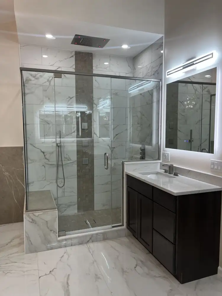 Another view: Primary bathroom with freestanding tub, glass chandelier, frameless glass shower with ceiling rain head and body jets, marble-look floor, Beachwood, Ohio