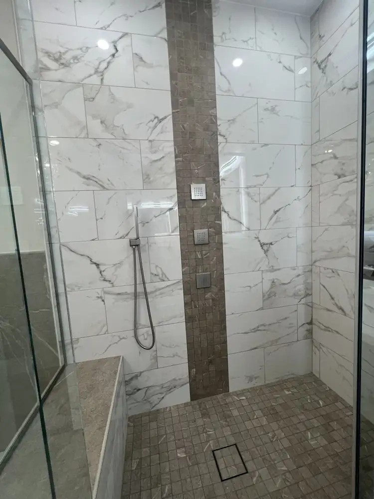Another view: Primary bathroom with freestanding tub, glass chandelier, frameless glass shower with ceiling rain head and body jets, marble-look floor, Beachwood, Ohio