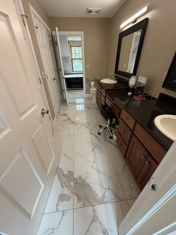 Another view: Black pedestal tub on a black-bordered marble-look tile inset under a dormer window, walk-in shower with bench, Chagrin Falls, Ohio
