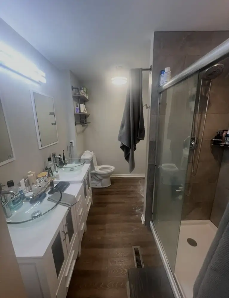 Bathroom with double vessel-sink vanity, fiberglass shower and wood-look vinyl floor before remodel, Chagrin Falls, Ohio
