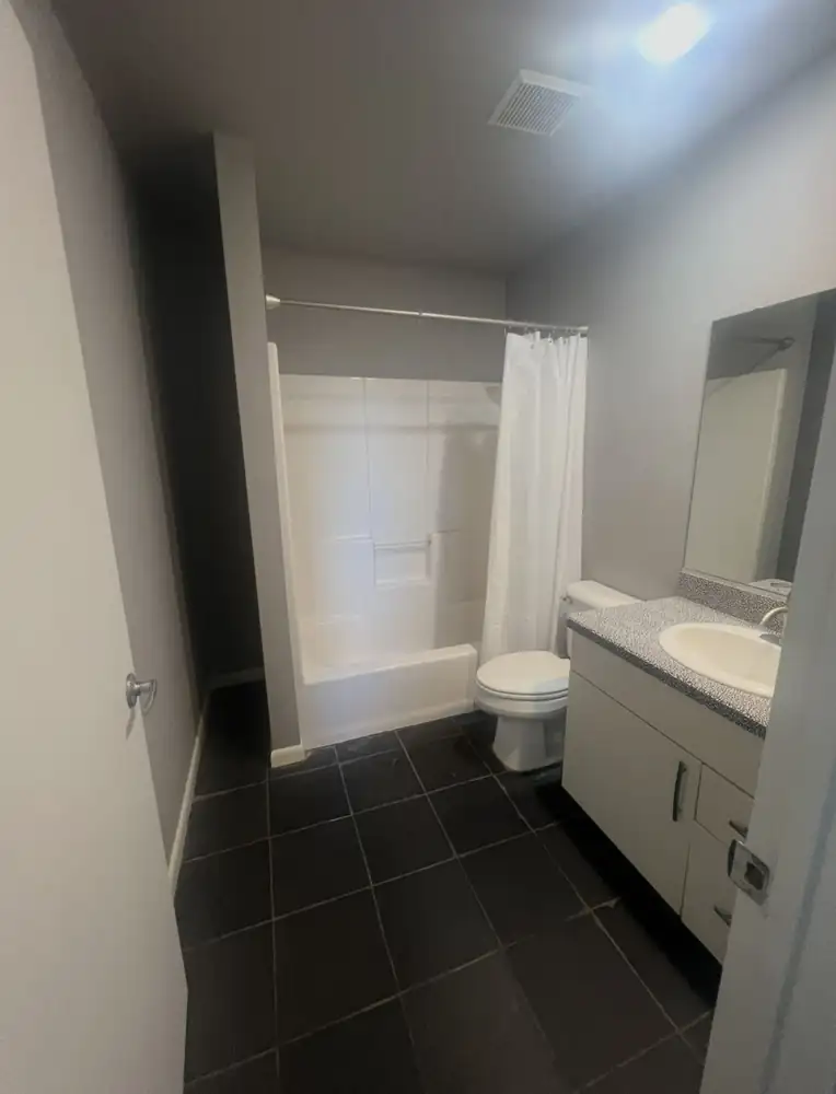 Bathroom with fiberglass tub surround, laminate vanity and dark tile floor before remodel, Cleveland, Ohio