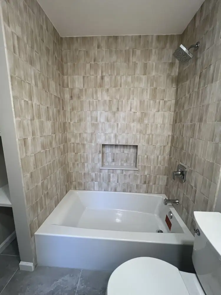 Another view: Bathroom with handmade-look vertical tile tub surround, built-in shelving, wood vanity and large gray porcelain floor, Cleveland, Ohio