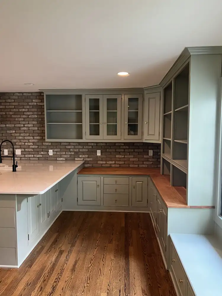 Kitchen cabinets and built-ins repainted sage green with brass knobs