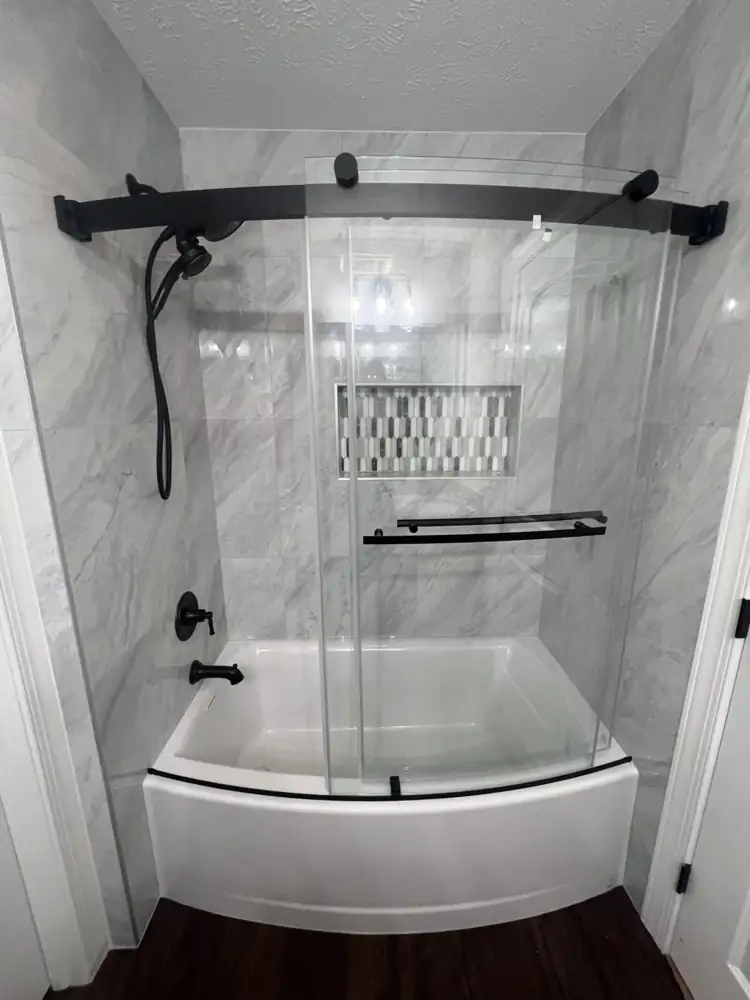 New tub with marble-look porcelain surround, curved sliding glass door and matte black fixtures, Macedonia, Ohio