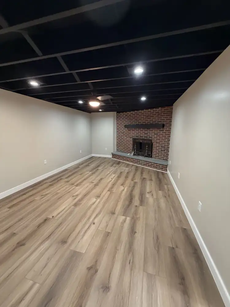 Basement family room with black open ceiling, recessed lights, brick fireplace and plank flooring, Ohio