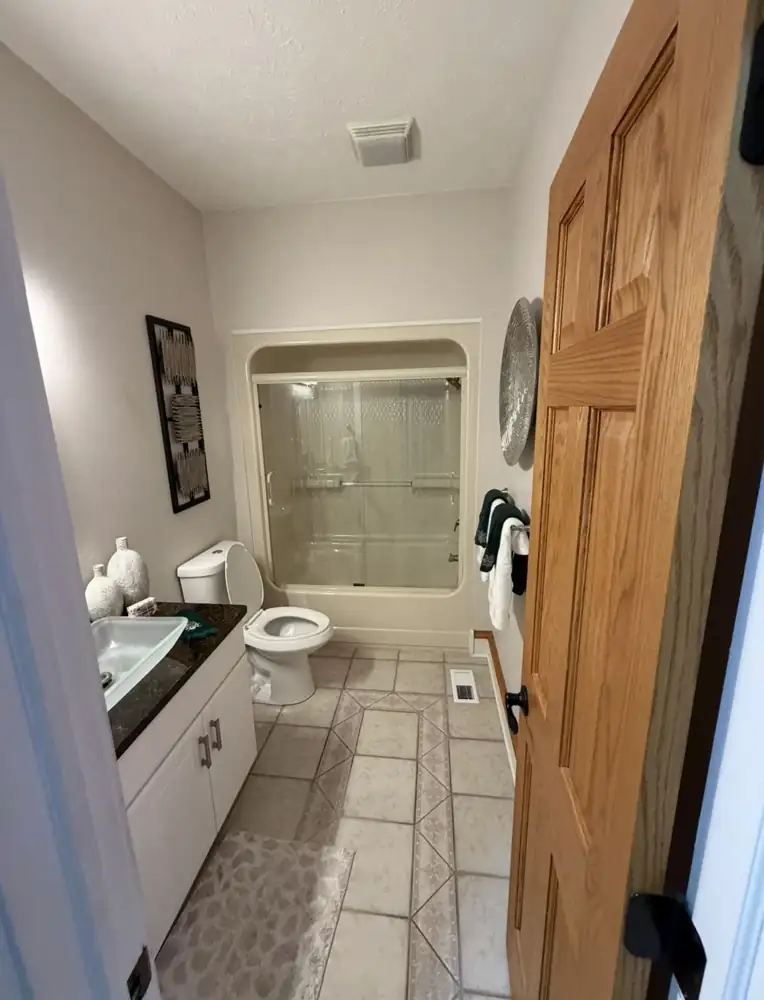 Bathroom with almond fiberglass tub unit and tile floor before remodel, Mentor, Ohio