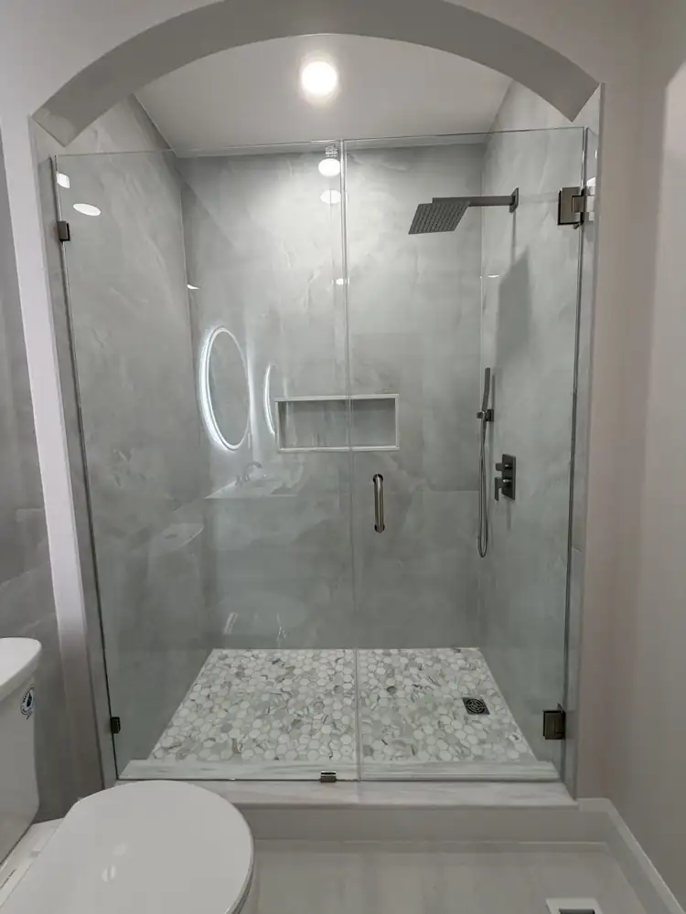 Another view: Bathroom with arched walk-in shower, large-format porcelain, round lighted mirror and fluted vanity, Mentor, Ohio
