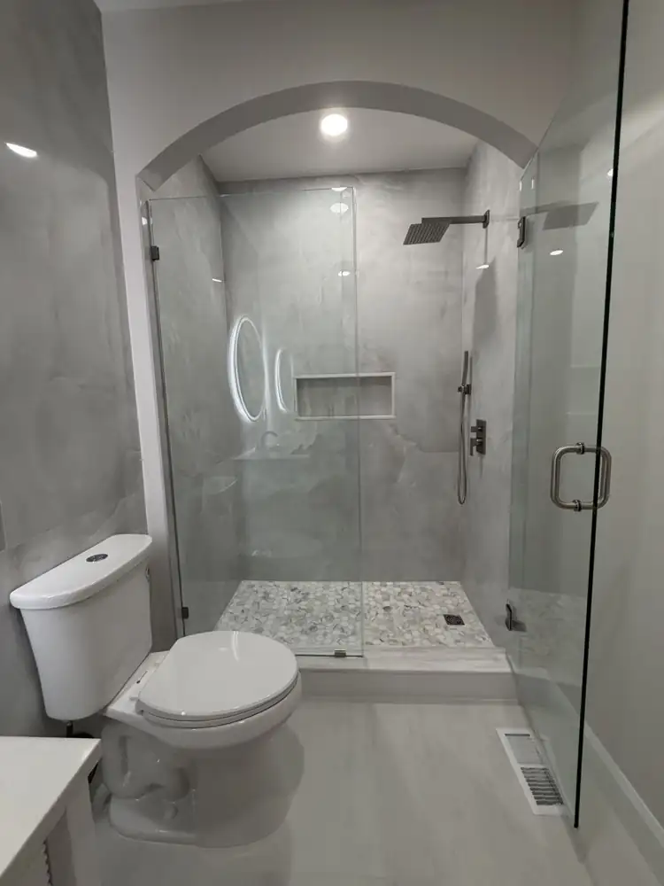 Another view: Bathroom with arched walk-in shower, large-format porcelain, round lighted mirror and fluted vanity, Mentor, Ohio