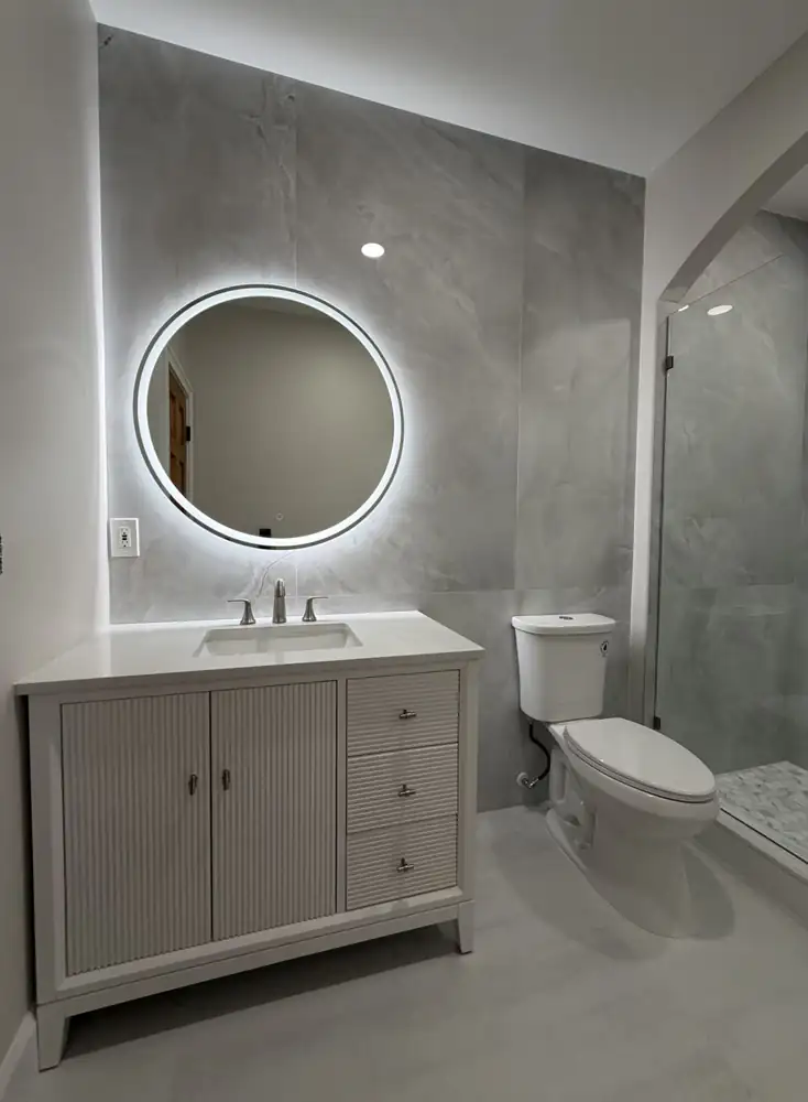 Another view: Bathroom with arched walk-in shower, large-format porcelain, round lighted mirror and fluted vanity, Mentor, Ohio