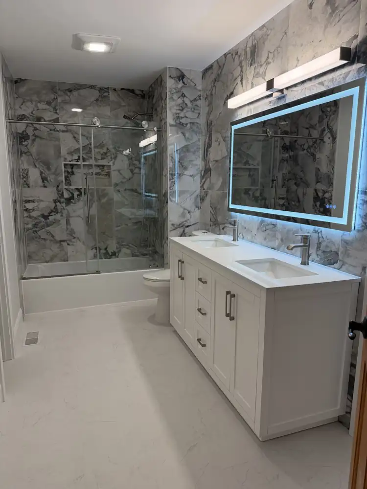 Hall bathroom with bold marble-look porcelain, sliding glass tub door and double vanity with lighted mirror, Mentor, Ohio