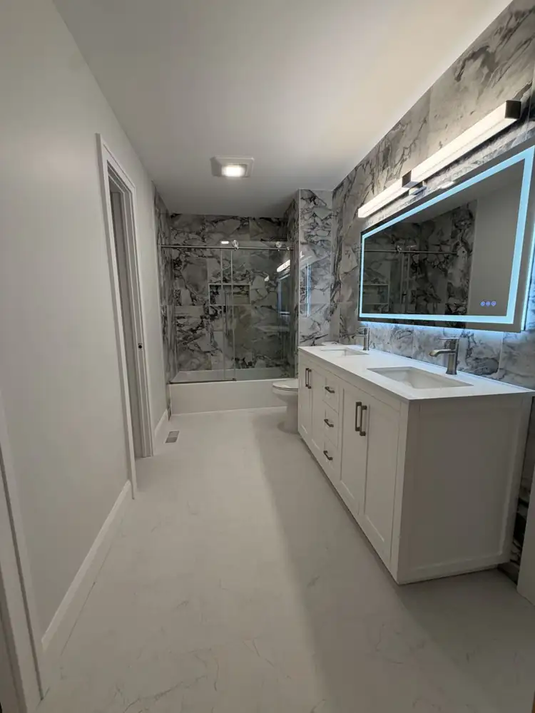 Another view: Hall bathroom with bold marble-look porcelain, sliding glass tub door and double vanity with lighted mirror, Mentor, Ohio