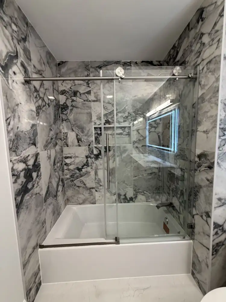 Another view: Hall bathroom with bold marble-look porcelain, sliding glass tub door and double vanity with lighted mirror, Mentor, Ohio