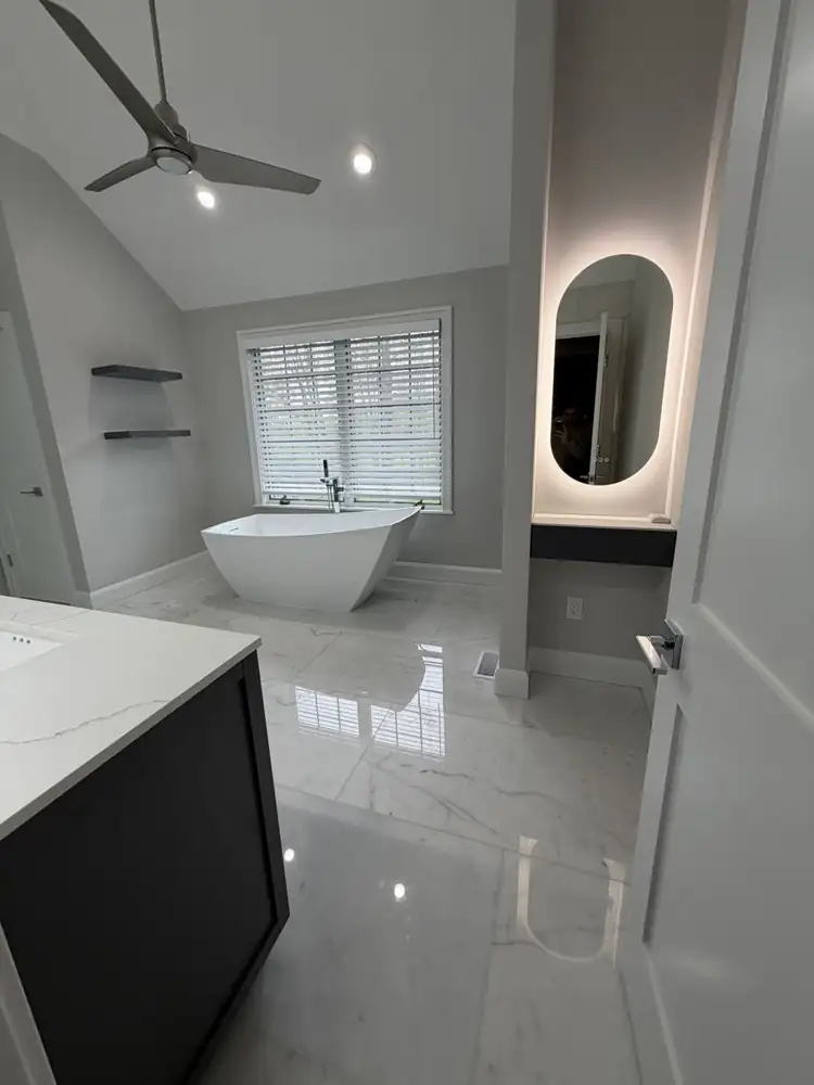 Another view: Primary bathroom with freestanding tub, glass shower, gray double vanity and marble-look floor under a vaulted ceiling, Mentor, Ohio