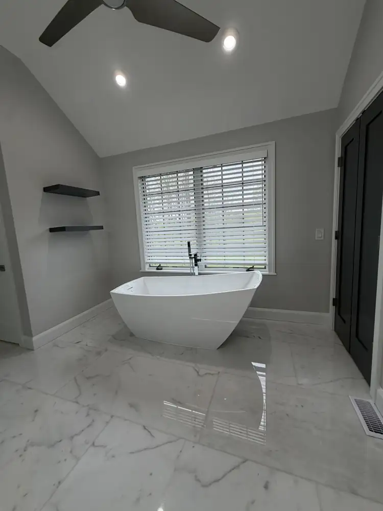 Another view: Primary bathroom with freestanding tub, glass shower, gray double vanity and marble-look floor under a vaulted ceiling, Mentor, Ohio