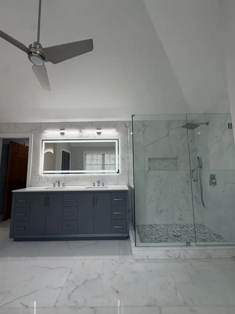Another view: Primary bathroom with freestanding tub, glass shower, gray double vanity and marble-look floor under a vaulted ceiling, Mentor, Ohio