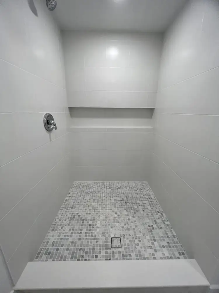 Walk-in shower with large white tile, marble mosaic floor, long niche and quartz curb, Northeast Ohio