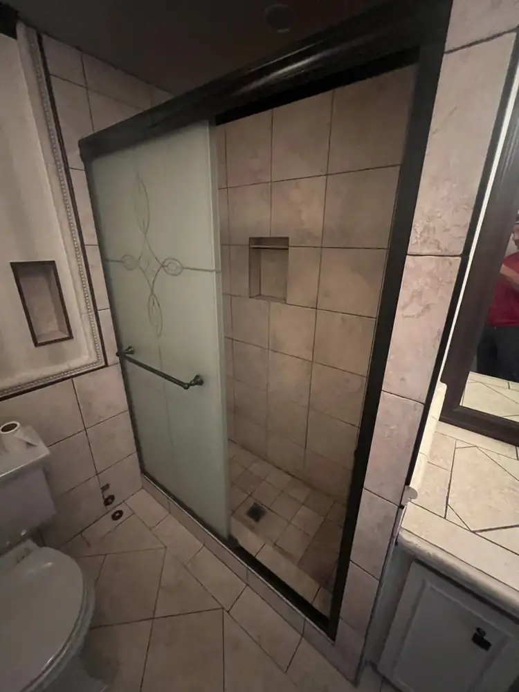 Dated tile shower with framed sliding glass door before remodel, Northeast Ohio