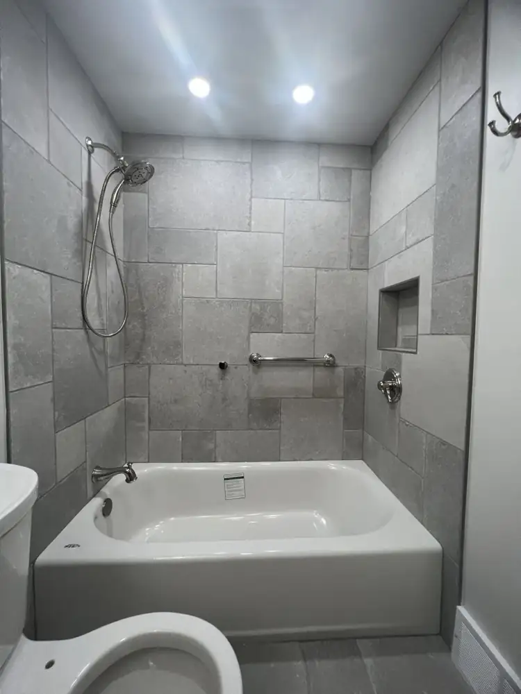Tub and shower with gray stone-look porcelain, handheld shower and brushed nickel fixtures, Gates Mills, Ohio