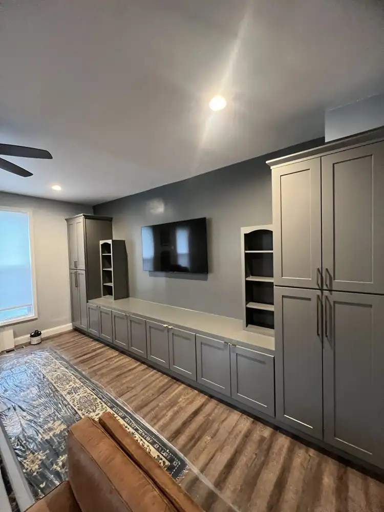 Built-in gray entertainment wall with floor-to-ceiling storage and wood-look plank floor, Northeast Ohio