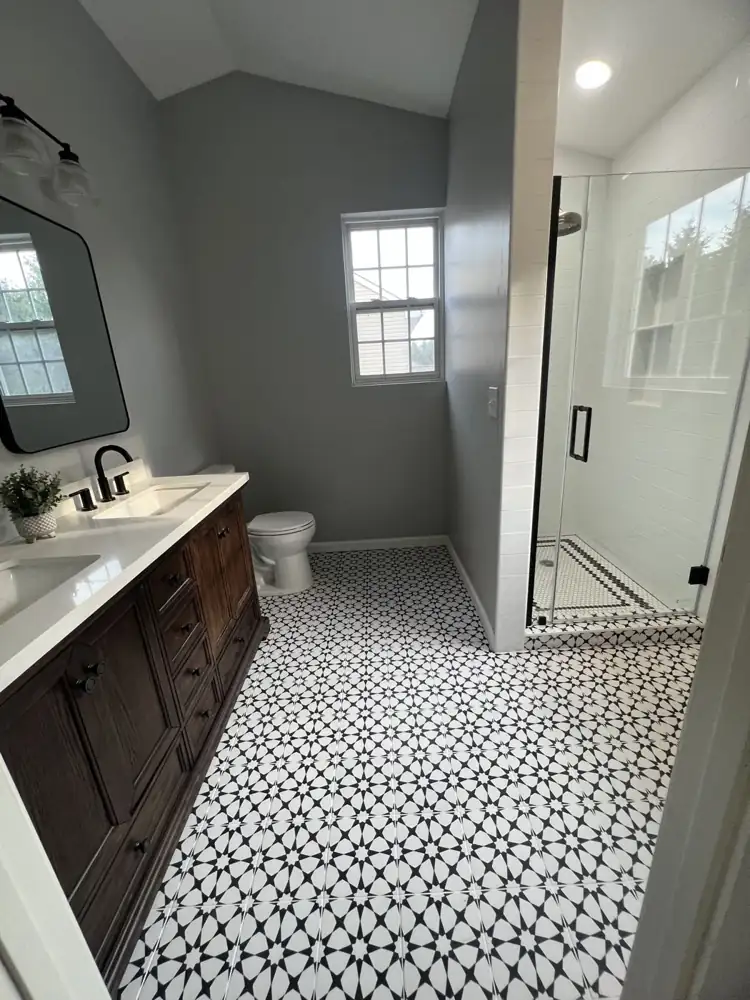 Bathroom with black and white star pattern tile floor, wood double vanity and frameless glass shower, Northeast Ohio