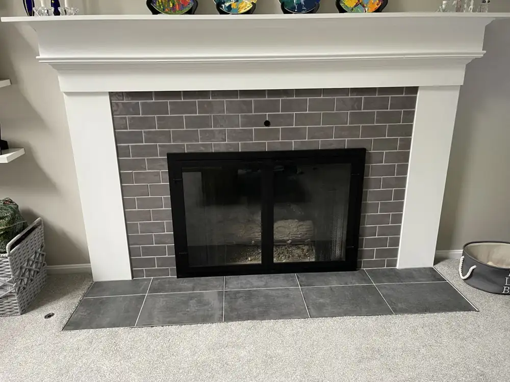 Gray subway tile fireplace surround with black glass doors and slate-look porcelain hearth, Northeast Ohio