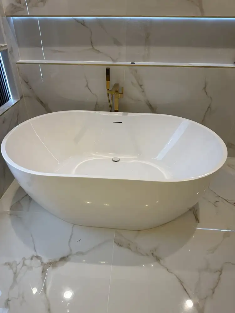 Oval freestanding tub on polished marble-look porcelain floor with gold tub filler, Northeast Ohio