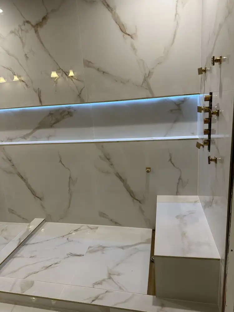 Walk-in shower with marble-look slab walls, gold thermostatic valve, six body jets and tiled bench, Northeast Ohio