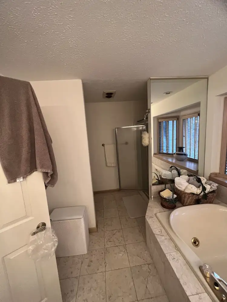 Primary bathroom with jetted tub deck and corner shower stall before remodel, Northeast Ohio