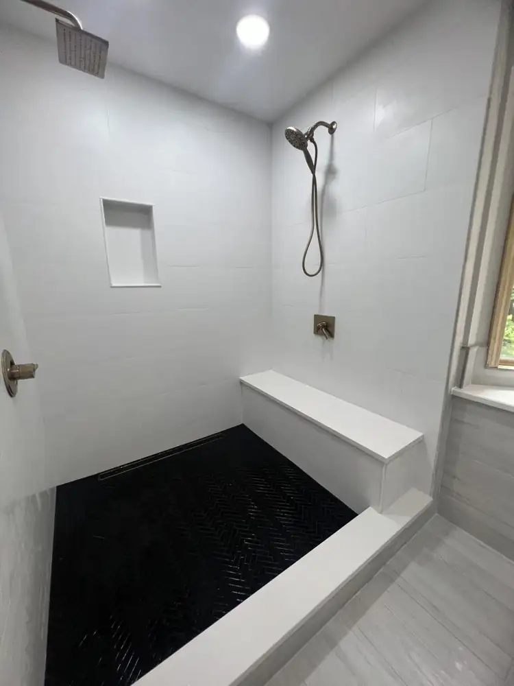 White tile shower with black herringbone mosaic floor and long quartz bench, Northeast Ohio