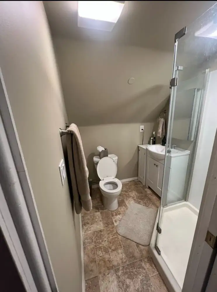 Small attic bathroom under a sloped ceiling with prefab shower before remodel, Northeast Ohio