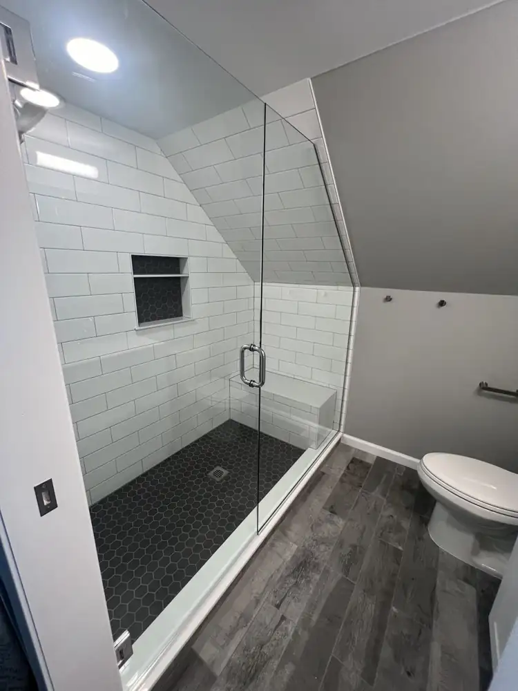 White subway tile shower with black hexagon floor, niche and tiled bench under the roofline, Northeast Ohio