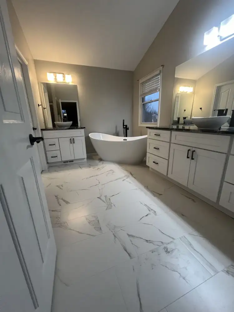 Primary bathroom with freestanding tub, white marble-look porcelain floor and two white shaker vanities, Northeast Ohio