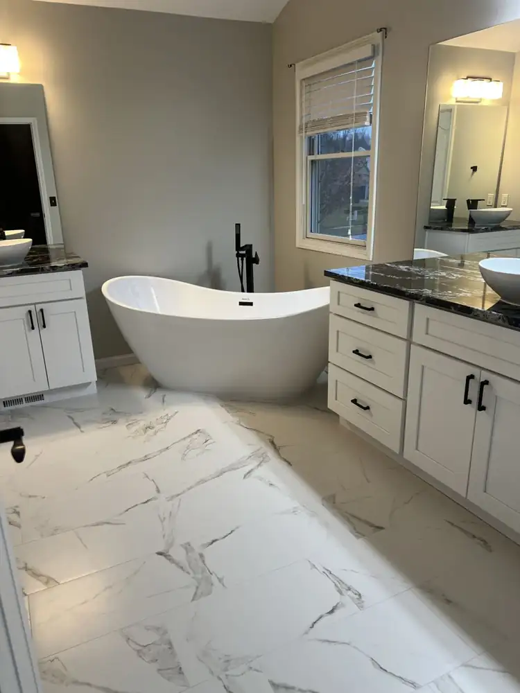 Freestanding tub with matte black floor-mount filler between two vanities with black granite tops, Northeast Ohio