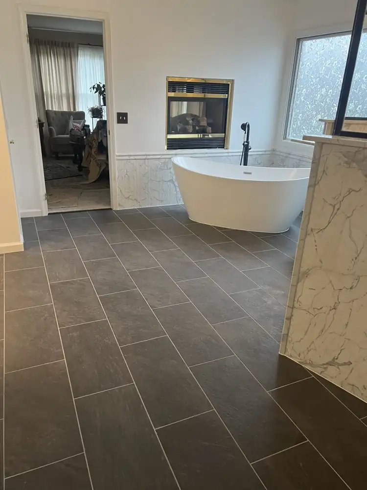 Primary bathroom with freestanding tub beside a gas fireplace and charcoal slate-look floor