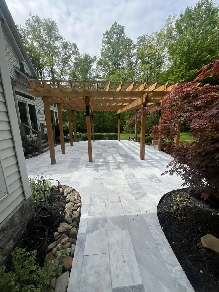 Gray marble paver patio under a cedar pergola with curved planting beds, Northeast Ohio