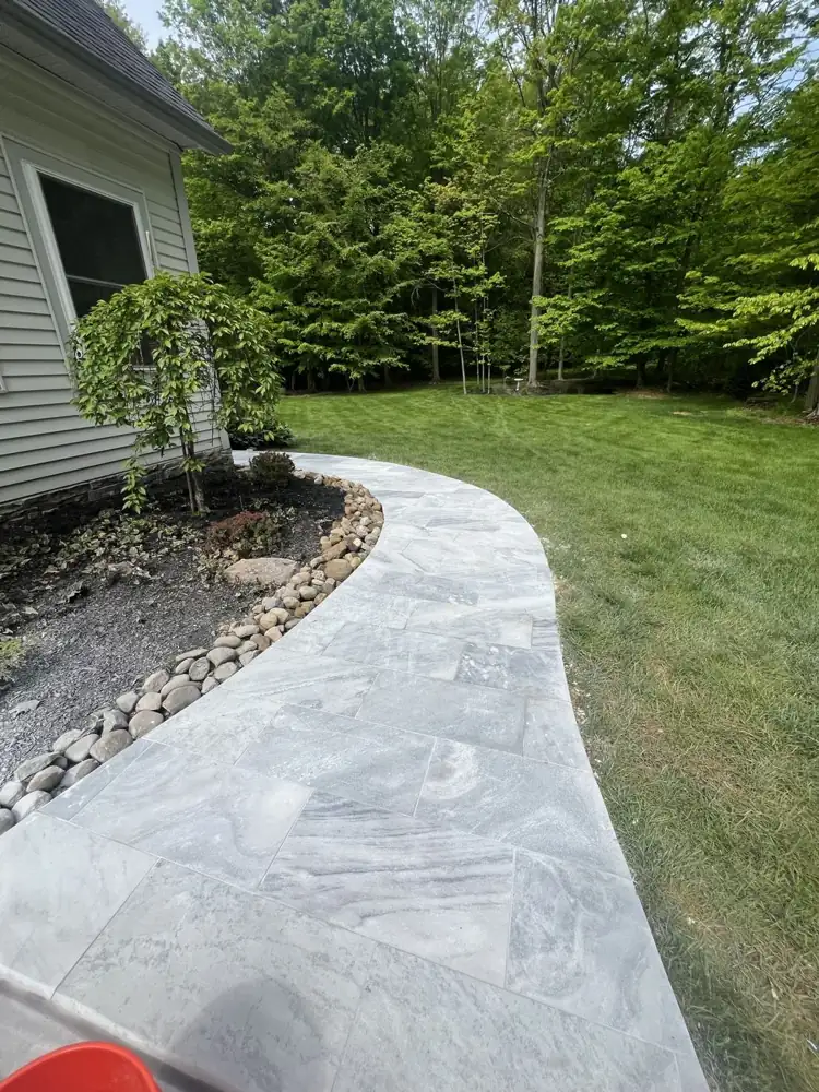 Curved gray marble walkway along the house with river rock border, Northeast Ohio
